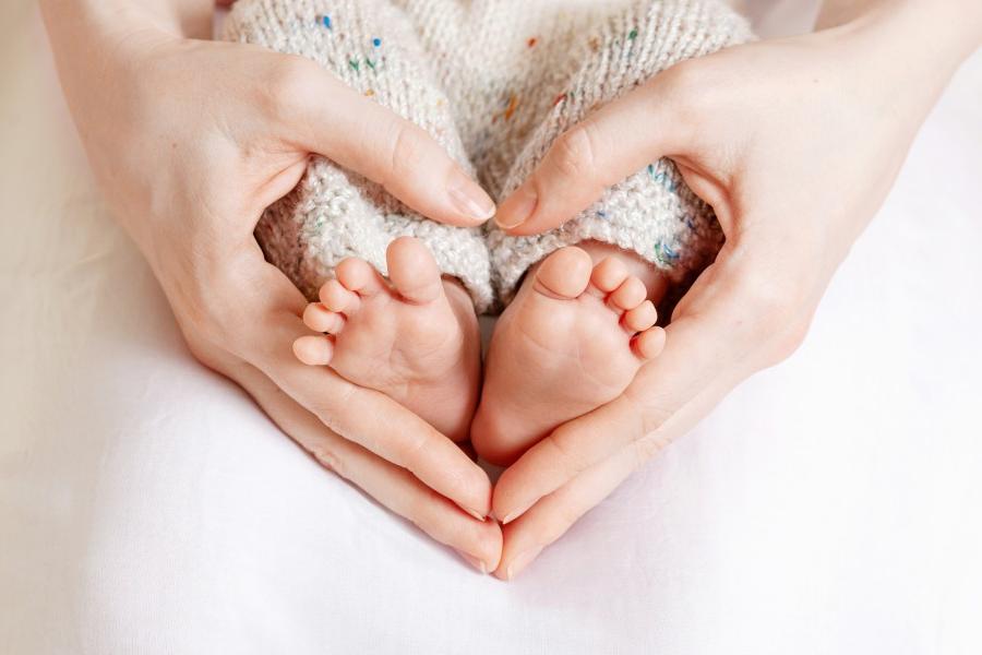 双手抱着婴儿的脚，呈心形